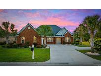 Charming brick home with manicured lawn, mature palm trees, and a spacious driveway under a beautiful pink and purple sky at 310 Babylon Pine Dr., Myrtle Beach, SC 29579