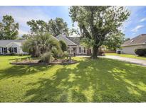 Charming single-story home featuring a well-manicured lawn, mature trees, and inviting landscaping at 3910 Stillwood Dr., Myrtle Beach, SC 29588