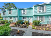 Charming townhomes with aqua siding, white shutters, landscaped yard, and brick steps leading to the front door at 7403 N Ocean Blvd. # C, Myrtle Beach, SC 29572