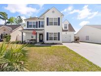 Charming two-story home features a well-manicured lawn, attached garage, and inviting front porch with blue accents at 104 Clovis Circle, Myrtle Beach, SC 29579