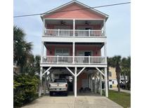 Charming three-story beach house with double balconies and covered parking nestled amongst lush palms at 124 Rainbow Dr., Murrells Inlet, SC 29576