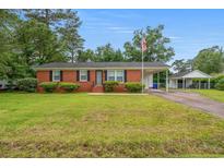 Charming brick home featuring manicured lawn, carport, and an American flag, perfect curb appeal at 203 Longwood Ln., Conway, SC 29527