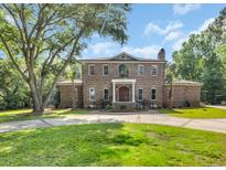 Stately brick home with mature trees, circular driveway, and a well-manicured lawn creates a welcoming entrance at 2382 Waverly Rd., Pawleys Island, SC 29585
