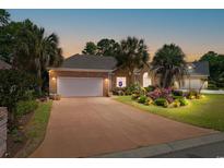 Charming brick home featuring a large driveway, garage, and lush landscaping with palm trees at 2567 Lake Vista Dr., Little River, SC 29566