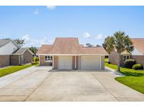 Wide shot of a brick home with a three car garage and large concrete driveway at 502 Garden Dr., Surfside Beach, SC 29575