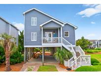 Charming coastal home featuring a raised foundation, blue siding, and a welcoming front porch with white railings at 6 Indigo Ct., Ocean Isle Beach, NC 28469