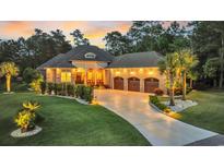 Elegant brick home featuring a three-car garage, manicured lawn, and inviting curb appeal at dusk at 81 Cascade Dr., Murrells Inlet, SC 29576