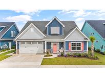 Charming two-story blue home with a two-car garage, a coral colored front door, and lush landscaping at 1008 Mary Read Dr., North Myrtle Beach, SC 29582
