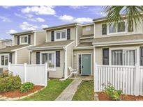 Inviting townhome with a well-manicured lawn and a charming white picket fence under a bright sky at 1600 Deer Creek Rd. # F, Myrtle Beach, SC 29575