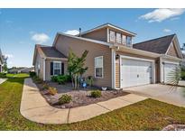 Inviting exterior view of townhome with well-maintained landscaping and attached garage, under a bright, blue sky at 1631 Hepburn Dr., Little River, SC 29566
