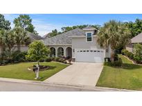 Beautiful home featuring a meticulously landscaped front yard, a two-car garage, and elegant architectural details at 2318 Via Palma Dr., North Myrtle Beach, SC 29582