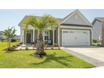 Charming single-Gathering home featuring a two-car garage, palm tree and well-manicured lawn at 5059 Sundrop Ln., Little River, SC 29566