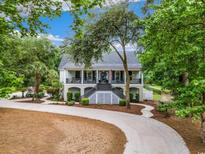 Charming two-story home with a long driveway and inviting front porch with black railings surrounded by large trees at 113 Trotter Trail, Georgetown, SC 29440