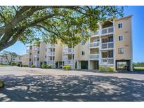 Coastal condos showcasing balconies and ground-level parking, enhanced by lush tree shade at 1912 Goose Creek Rd. Sw # 4302, Ocean Isle Beach, NC 28469