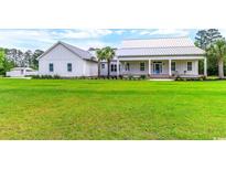 Charming single-story home with a sprawling green lawn and a welcoming front porch with rocking chairs at 3718 Highway 931, Conway, SC 29526