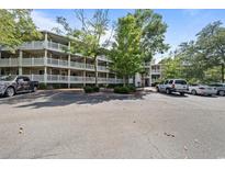 Condo exterior with white railings on balconies, trees, and parking lot view under a blue sky at 415 Ocean Creek Dr. # 2388, Myrtle Beach, SC 29572