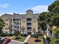Attractive condo building featuring a yellow facade, multiple balconies, manicured landscaping, and ample parking at 601 Hillside Dr. N # 2135, North Myrtle Beach, SC 29582
