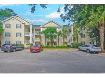 Exterior of a yellow condominium building with parking in front and surrounding palm trees on a sunny day at 601 N Hillside Dr. # 4434, North Myrtle Beach, SC 29582