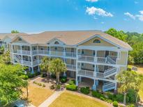 Three-story condo building featuring private balconies, lush landscaping, and convenient exterior staircases at 6203 Catalina Dr. # 1333, North Myrtle Beach, SC 29582
