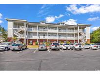 Three-story condo with white balconies, brick accents, and ample parking under a blue sky at 701 Salleyport Dr. # 1110, Myrtle Beach, SC 29579