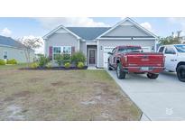 Charming single-story home with gray siding, a well-manicured lawn, and a driveway with two pickup trucks at 715 Tattlesbury Dr., Conway, SC 29526