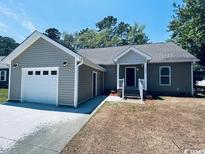 Tan single story home featuring an attached garage, gray roof, manicured lawn and welcoming front porch at 1000 Weldon Ln., Conway, SC 29526