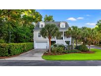 Charming two-story home with a well-manicured lawn, lush greenery, and a welcoming front porch at 12 Jerry Ct., Pawleys Island, SC 29585