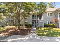 Inviting two-story condo with light gray siding, a beautiful tree and well-maintained landscaping at 1221 Tidewater Dr. # 2112, North Myrtle Beach, SC 29582
