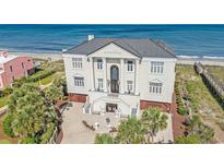 An opulent oceanfront home with classic architecture, including columns and a grand entrance, and a meticulously maintained landscaped yard at 123 Pioneer Loop, Georgetown, SC 29440