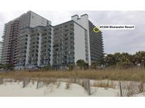 Exterior shot of the condominium building at Bluewater Resort with beach vegetation in the foreground at 2001 S Ocean Blvd. # 1504, Myrtle Beach, SC 29577