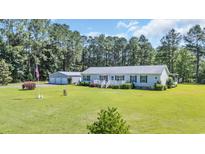 Ranch-style home boasts a manicured lawn, detached garage, and covered front porch, perfect for relaxing at 203 Warbler St., Georgetown, SC 29440
