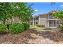 Exterior view of a two-story building with tan siding, white trim, and multiple balconies, nestled among mature trees at 3104 Sweetwater Blvd. # 3104, Murrells Inlet, SC 29576