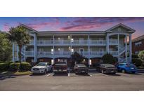 Three-story condo building with white balconies and stairs, and multiple parked cars at 3939 Gladiola Ct. # 202, Myrtle Beach, SC 29588