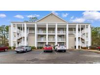 Attractive condo building with multiple stories, external stairs, and ample parking in a serene community setting at 5870 Longwood Dr. # 201, Murrells Inlet, SC 29576