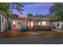 Charming home featuring a cozy front porch, vibrant pink doors, and a fun, welcoming beach vibe at 6001-1643 S Kings Hwy., Myrtle Beach, SC 29575