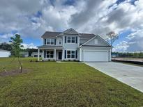 Charming two-story home with a manicured lawn and attached two-car garage at 9409 Long Meadow Way, Longs, SC 29568