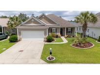 Charming single-story home featuring a well-manicured lawn, two-car garage, and inviting landscaping at 1224 Checkerberry St., Longs, SC 29568