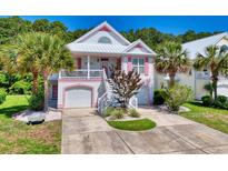 Charming two-story home with pink trim, a white metal roof, landscaped yard, and a two-car garage at 146 Georges Bay Rd., Surfside Beach, SC 29575