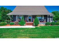 Charming log cabin-style home with a metal roof, landscaped front yard, and inviting porch at 181 Halfway Rd., Nichols, SC 29581