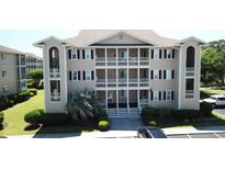 A beige three-story condo building featuring white railings, black shutters, and manicured landscaping at 1900 Duffy St. # L-5, North Myrtle Beach, SC 29582
