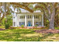 Stately white home featuring a grand front porch with large columns and a manicured lawn shaded by mature trees at 21 Whitehall Ave., Georgetown, SC 29440