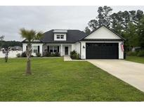 Charming one-story home featuring black accents, a well-manicured lawn, and a black two-car garage door at 2529 Suzanne Dr., Conway, SC 29526