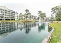 Scenic pond view with fountain and condominium buildings in the background under a cloudy sky at 305 N Hillside Dr. # 206, North Myrtle Beach, SC 29582