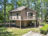 Unique home with tan siding and a deck sits among mature trees at 752 Tall Oaks Ct., Myrtle Beach, SC 29588