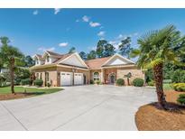 Stately brick home with a three-car garage, manicured lawn, and mature palm trees creates a welcoming atmosphere at 784 Caines Landing Rd., Conway, SC 29526