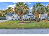 Charming brick home featuring a well-manicured lawn and mature palm trees at 156 Hummingbird Ct., Myrtle Beach, SC 29579