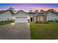 Charming single-story home with a two-car garage and manicured lawn against a twilight sky at 1620 San Andres Ave., Little River, SC 29566