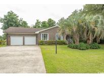 Charming brick home with a well-manicured lawn and mature landscaping at 18 Pine Valley Ln., Surfside Beach, SC 29575