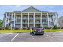 Three-story condo building featuring elevated decks, white columns, and lush landscaping at 5852 Longwood Dr. # 302, Murrells Inlet, SC 29576
