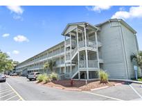 Exterior view of the building with multiple levels and outdoor staircases, complemented by landscaping and parking at 5905 South Kings Hwy. # 5202, Myrtle Beach, SC 29575